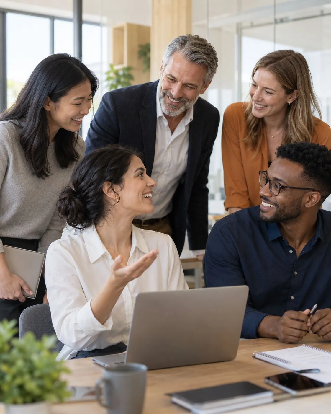 Une équipe de collaborateurs souriants échange autour d’un ordinateur portable